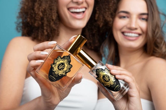 Two women joyfully showcasing luxury perfumes, ideal for gifts at a perfume shop, emphasizing beauty and fragrance.