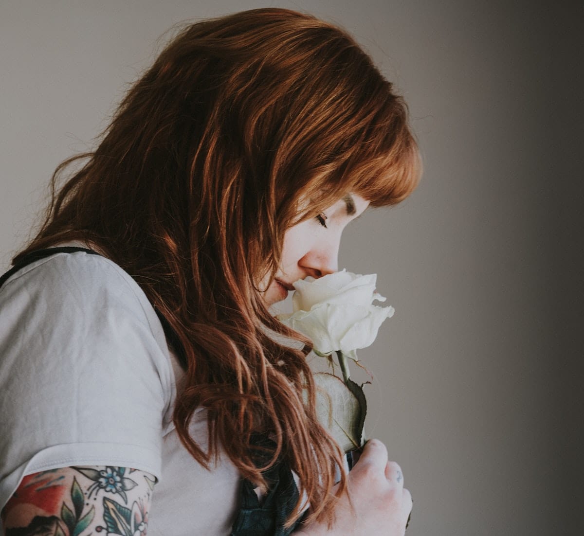 Woman enjoying fragrance of a white rose, representing perfume online Ireland 101: buy perfumes online safely with gift cards.