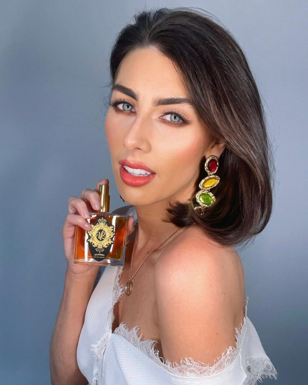 Stylish woman holding Valley of Roses perfume bottle, illustrating how to wear perfume and wear it well for optimal fragrance use.