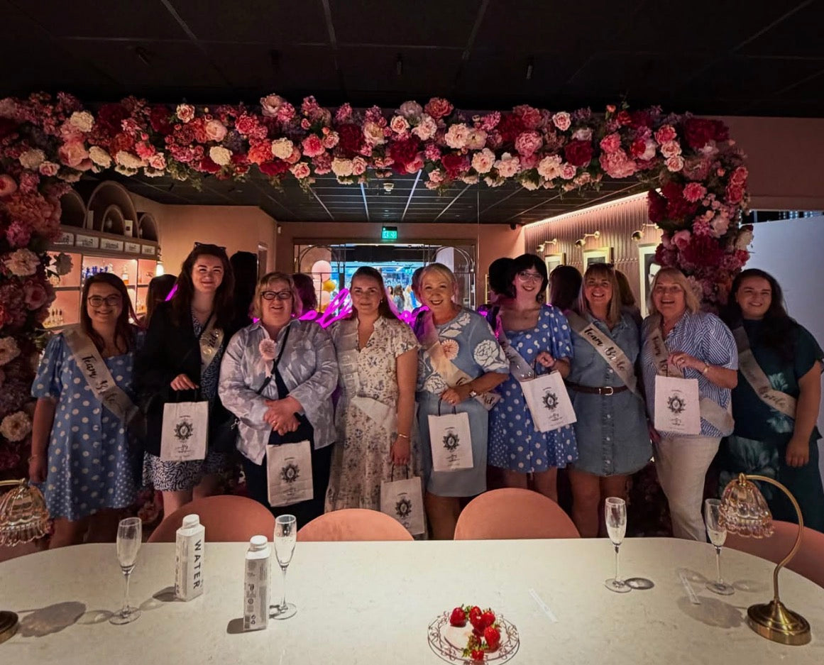 Hen party group at Valley of Roses Kilkenny - women celebrating with goodie bags under a floral arch