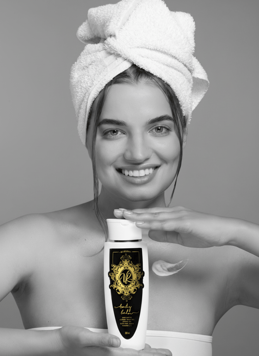 Woman with towel on head holding a bottle of skincare product