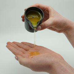 Silk Kiss Soothing Candle | Truffle and Chocolate pouring soothing oil into hand for moisturising and relaxation.